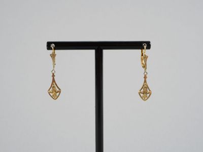 une paire de boucles d'oreilles en or posée sur un support noir