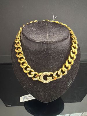 un collier à chaîne en or et un chapeau exposés dans une vitrine