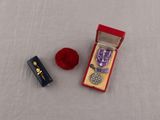 une petite boîte contenant une médaille et une pelote de laine rouge