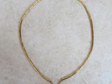 a close up of a gold necklace on a marble surface