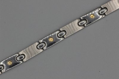 un gros plan d'un bracelet en argent et en or posé sur une surface grise