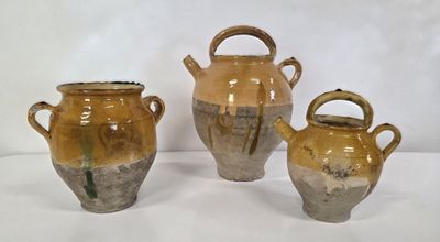 trois vases marron posés sur une surface blanche, sur fond blanc