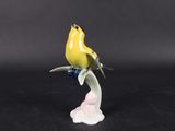 a small figurine of a yellow bird on a branch