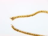 a close up of a gold chain on a white surface