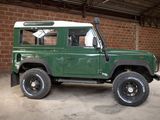 a green land rover with a white top parked in a garage