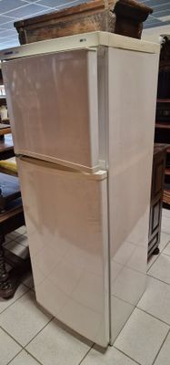 un réfrigérateur blanc posé dans une pièce, à côté d'une table