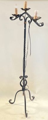 wrought iron candelab with candles on top of it against a white wall