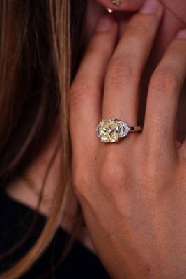 close up of a woman ' s hand holding a yellow and white diamond ring