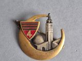 a gold brooch with a clock tower and a crescent on it