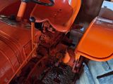 an orange tractor sitting in a garage with a red seat