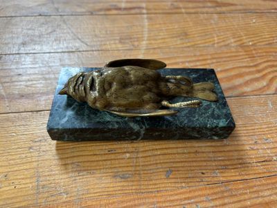 une statue en bronze représentant un poisson, posée sur un bloc de marbre