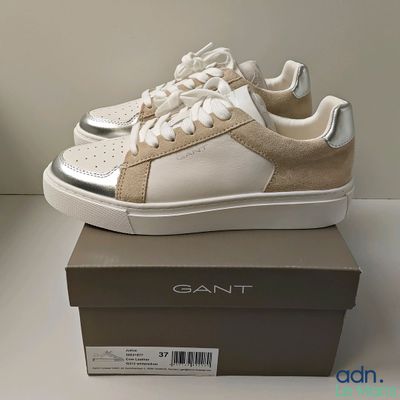 the white and gold sneakers are sitting on top of a box