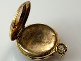 a gold pocket watch sitting on a white surface