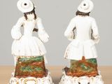 two figurines of women in white dresses on a table