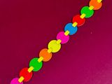 a close up of a rainbow colored bracelet on a pink surface