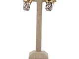 pair of silver and gold earrings on a stand on a white background