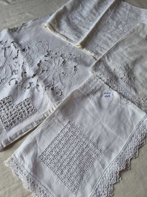 quatre serviettes de table en lin blanc ornées de motifs brodés, posées sur une table