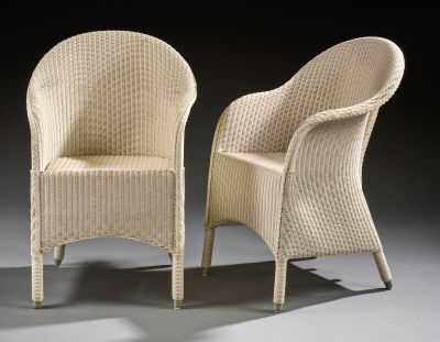 pair of white wicker chairs against a black background