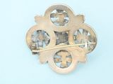 a gold brooch on a light blue surface