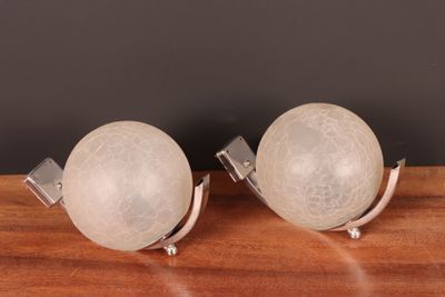 pair of white glass globes on metal bases on a wooden table