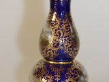 a blue and gold vase sitting on a white surface