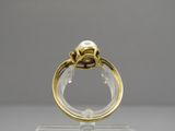 gros plan d'une bague en or contenant une perle