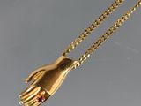 un gros plan sur un collier en or avec une main accrochée à une chaîne