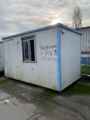 a small white building with a blue roof in a parking lot