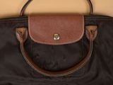 brown and black handbag with a brown handle on a beige background