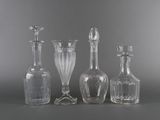 three clear glass vases and a bottle on a gray surface
