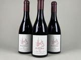 trois bouteilles de vin rouge posées sur une table
