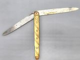 a knife with a gold handle on a gray surface