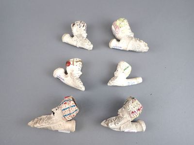 plusieurs petites figurines en céramique représentant des chaussures et des chapeaux, posées sur une surface grise