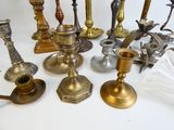 many different types of candles and candlesticks on the table