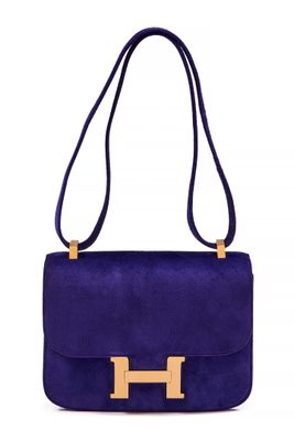 a purple sued handbag with a gold metal handle