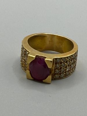 bague en or jaune sertie d'une pierre rouge entourée de diamants blancs
