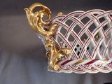 a white and red basket with a gold handle on a table