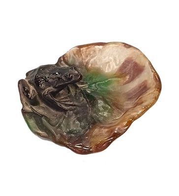 a figurine of a frog sitting on a shell