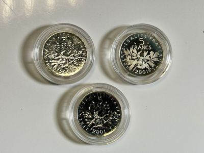 trois pièces de monnaie dans des boîtes en plastique posées sur une surface blanche