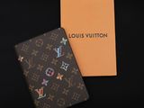 un étui à passeport Louis Vuitton et une boîte sur fond noir