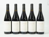 quatre bouteilles de vin sont alignées sur une surface blanche
