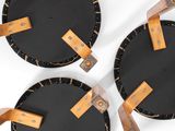three black plates with brown leather handles on a white surface