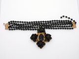 a close up of a black beaded necklace on a white surface
