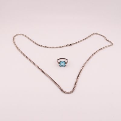 un collier en argent orné d'une pierre bleue et d'une chaîne, sur fond blanc