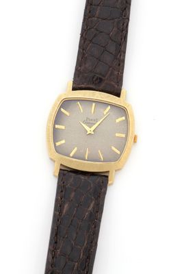 a close up of a watch on a white surface with a brown strap