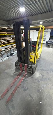 un chariot élévateur jaune dans un entrepôt où s'alignent des rayonnages de palettes