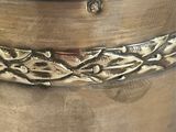 a silver container with a braid design on it