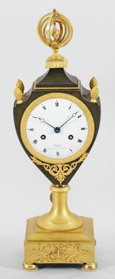 a black and gold clock on a stand on a white background