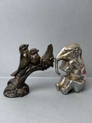 a silver figurine of an elephant and an elephant with a bird on its head