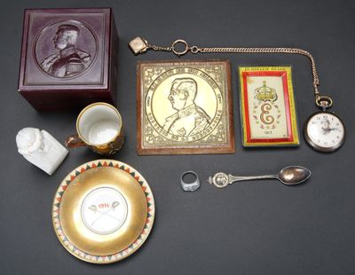 une assiette en or sur laquelle figure le portrait d'un homme, à côté d'autres objets